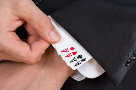 Close-up Of Businessman Hand Removing Ace Cards From Sleeveの写真素材