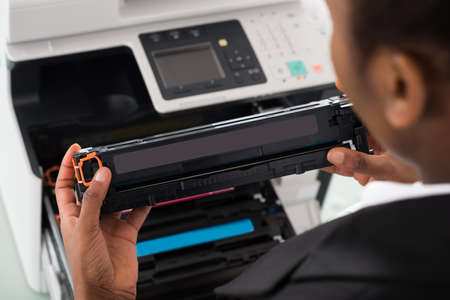 Young African Businesswoman Fixing Cartridge Near Photocopy Machine In Office