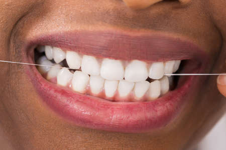 Close-up Of Young African Woman Flossing Teethの写真素材