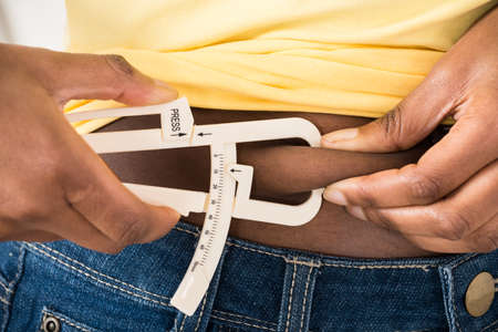 Close-up Of Young Woman Measuring Fats With Caliperの写真素材