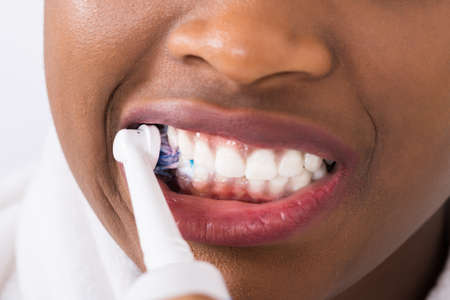Close-up Of An Young African Woman Brushing Teeth With Electric Toothbrush