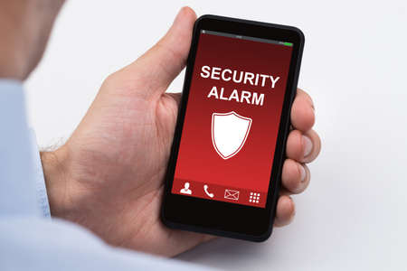 Close-up Of Businessperson Holding Mobile Phone Showing Security Alarmの写真素材