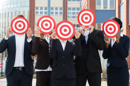 Group Of Professional Businesspeople Hiding Face With Red Dartboardの写真素材