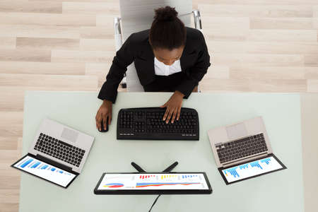 High Angle View Of A Young African Woman Analyzing Graph In Office
