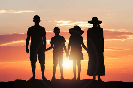 Silhouette Of A Family Holding Hands Together Against Dramatic Skyの写真素材
