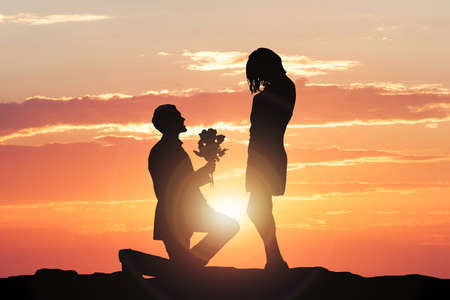 Silhouette Of A Man Making Proposal To Woman During Sunsetの写真素材