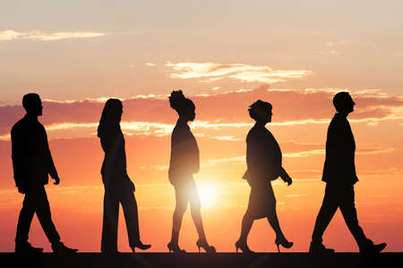 Silhouette Of Multiethnic People Walking At Sunsetの写真素材