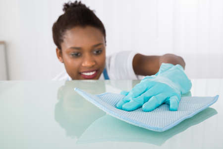 Happy Young Female Janitor Cleaning Desk With Ragの写真素材