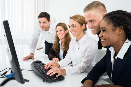 Team Of Businesspeople Looking At Computer In Office