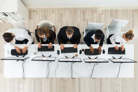 High Angle View Of Call Center Operators Working On Computers In Office