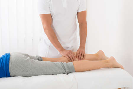 Close-up Of Man Giving Leg Massage To Woman In Spa