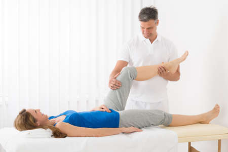 Happy Mature Woman On Bed Receiving Leg Massage In Spa