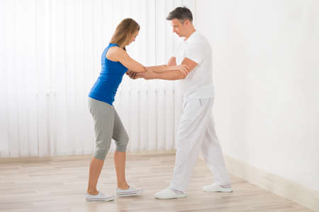 Physiotherapist Assisting Happy Mature Woman For Exercising