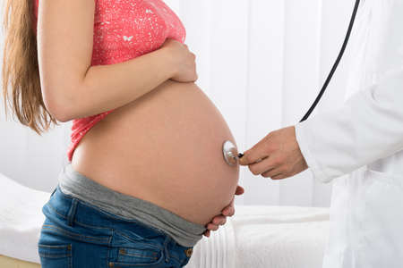 Close-up Of Doctor Examining Pregnant Woman With Stethoscopeの写真素材