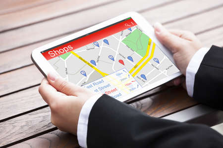 Close-up Of Person's Hand Using GPS Navigation On Digital Tablet To Find Shops