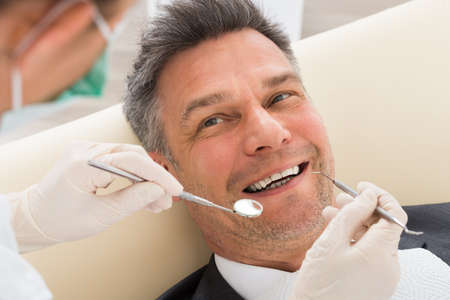 Happy Mature Man Having Dental Check-up In Clinic