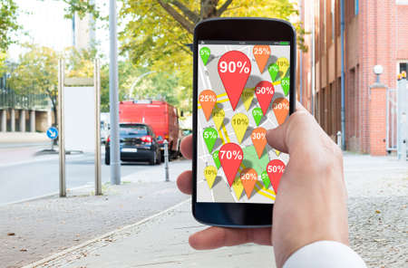 Close-up Of Person's Hand Using Mobile Phone With Discount Pin Map Marker