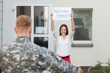 Happy Female Welcoming Her Husband Home From Army Leaveの写真素材