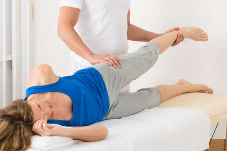 Happy Male Therapist Giving Leg Massage To Mature Womanの写真素材