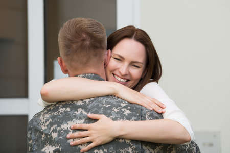 Portrait Of Happy Wife Hugging Her Husband In Army Uniformの写真素材