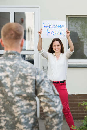 Happy Female Welcoming Her Husband Home From Army Leaveの写真素材