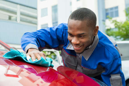 Young Happy Male Worker Cleaning Red Car With Clothの写真素材