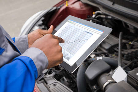 Close-up Of Mechanic With Digital Tablet Showing Graph While Examining Car
