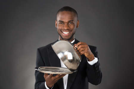 Portrait Of Happy Waiter Serving Meal In Clocheの写真素材