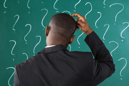 Rear View Of African Businessman In Front Of Chalkboard With Question Mark Signの写真素材