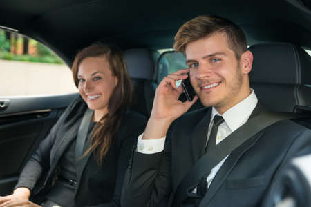 Portrait Of Young Smiling Businessman And Businesswoman Traveling In The Carの写真素材