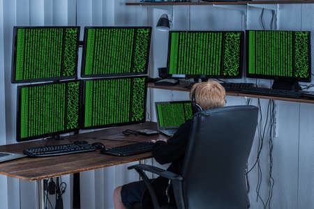 Child Using Multiple Computers With Binary Code On Screenの写真素材