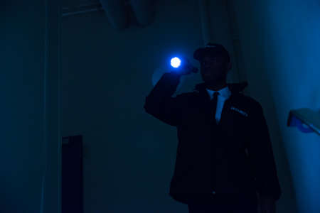 Male Security Guard In Black Uniform Holding Flashlightの写真素材