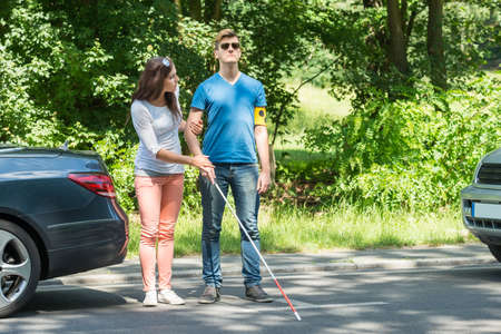 Young Woman Helping Blind Man Wearing Armband On Streetの写真素材