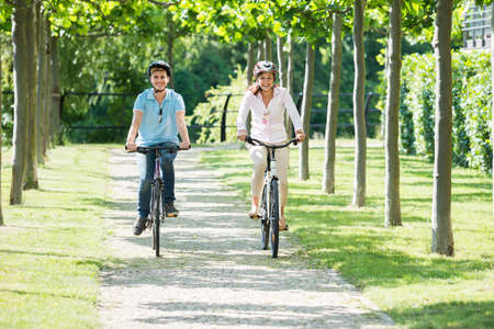Happy Young Couple Enjoying The Ride On Bicycles In Parkの写真素材