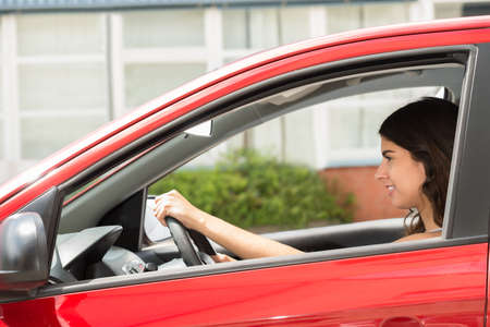 Side View Of A Young Happy Woman Driving Car