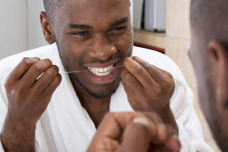 African Young Man Cleaning His Teeth In Front Of Mirrorの写真素材
