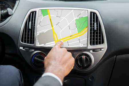 Close-up Of Person's Hand Using GPS Navigation System In Car