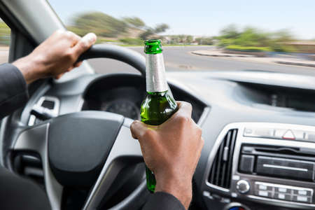 Close-up Of A Young African Businessman Holding Beer While Driving Carの写真素材