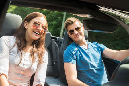 Portrait Of Smiling Young Couple In A Car Wearing Sunglassesの写真素材