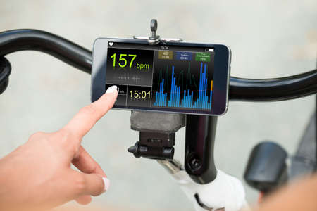Close-up Of Human Hand Pointing At Smart Phone Showing Heartbeat Rate On Bicycle