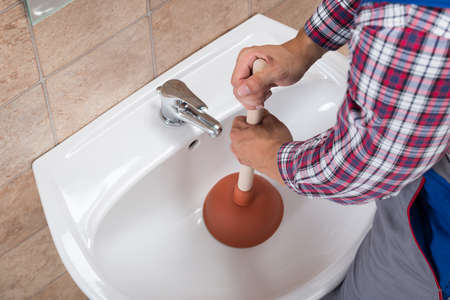 Close-up Of A Plumber Using Plunger In Bathroom Sinkの写真素材