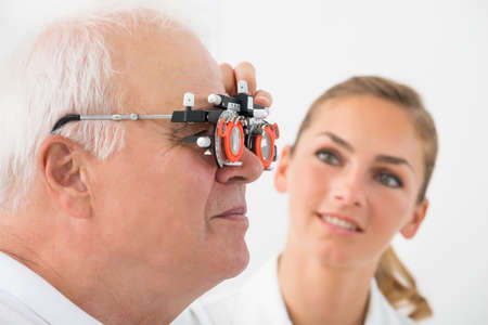 Close-up Of An Optometrist Checking Senior Male Patient Vision With Trial Frame At Eye Clinic