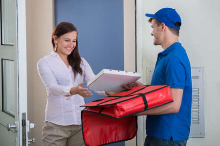 Friendly Delivery Man Handing Pizza To A Customer