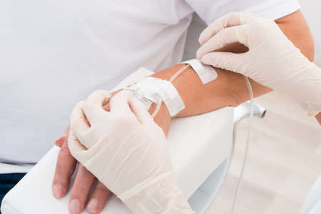Close-up Of Doctor's Hand With Iv Drip Inserted In Patient's Hand