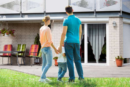 Rear View Of A Family Standing In Front Of Their New Houseの写真素材