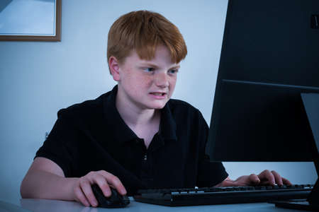 Angry Boy Sitting On Chair Working On Computer At Homeの写真素材