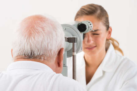 Happy Female Optometrist Doing Sight Testing For Patient In Clinic