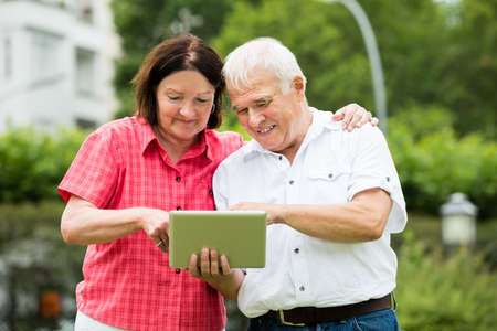 Happy Senior Couple Looking At Digital Tablet
