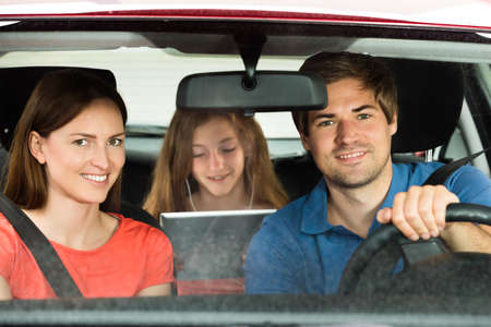Happy Parent With Their Daughter Traveling By Carの写真素材