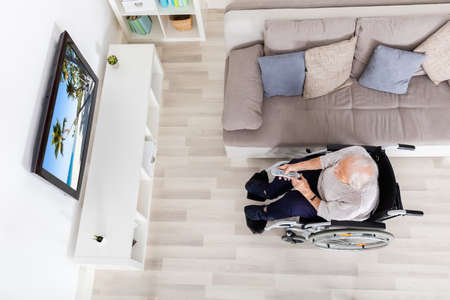 High Angle View Of Elder Woman Watching Movie On Television At Home